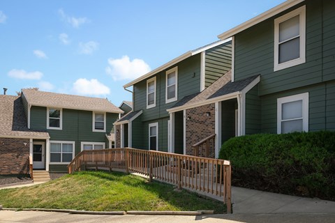 a row of green apartment buildings with a wooden deck