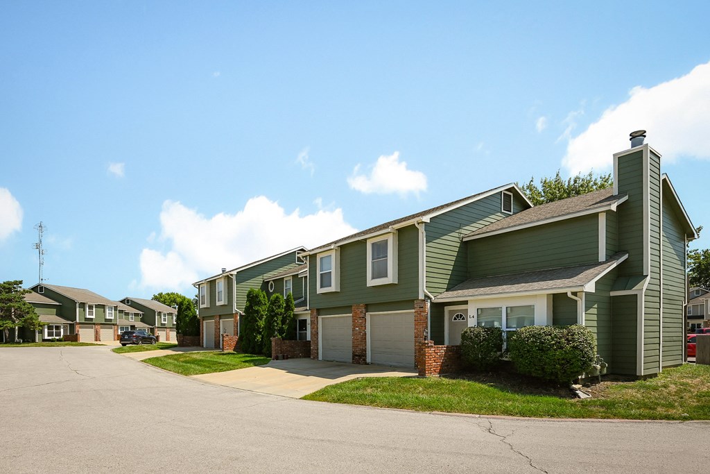 a row of green houses on the side of a street