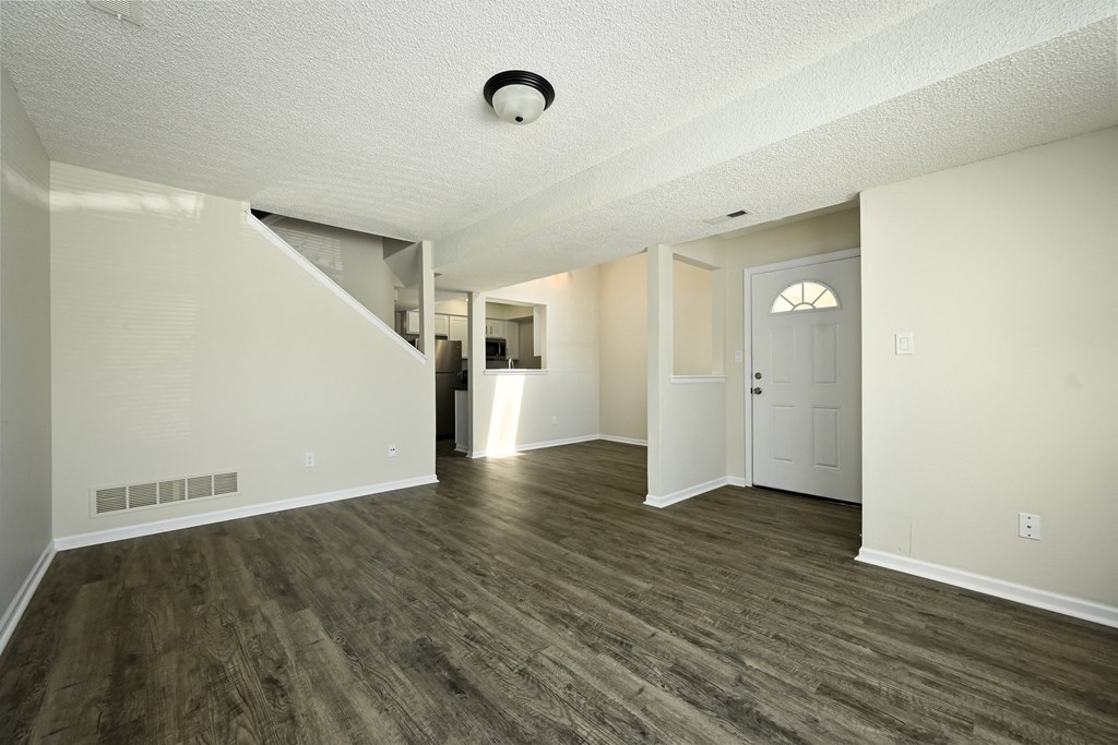 an empty living room with wood flooring and a white door