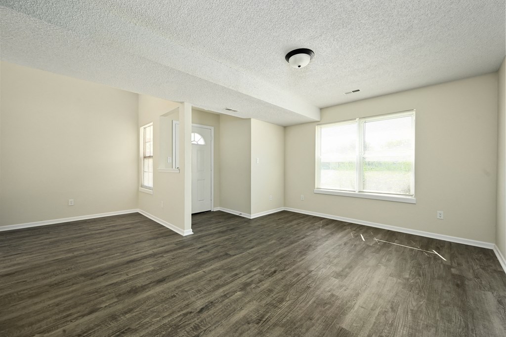 an empty living room with wood flooring and a window