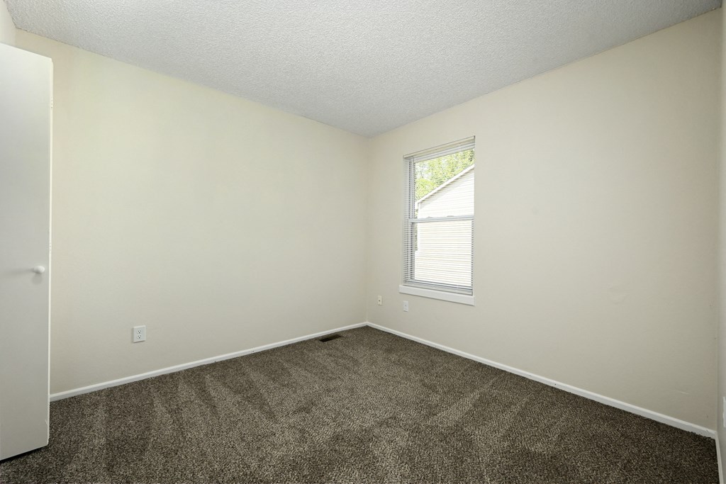 an empty bedroom with carpet and a window