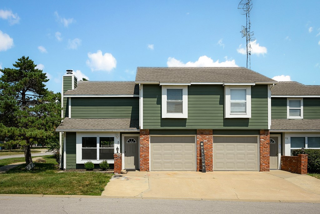 the front of a green house with a garage door