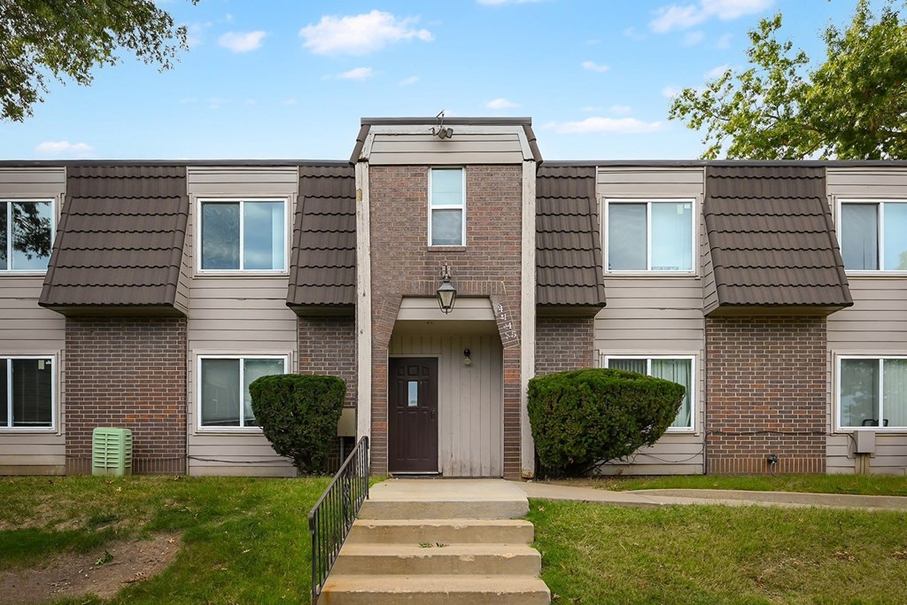 A brick house with a brown door and a small porch.