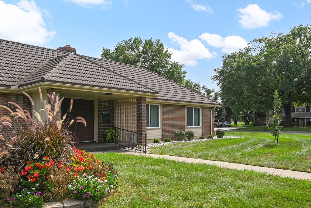 A house with a brown roof and a small front yard with a flower bed.