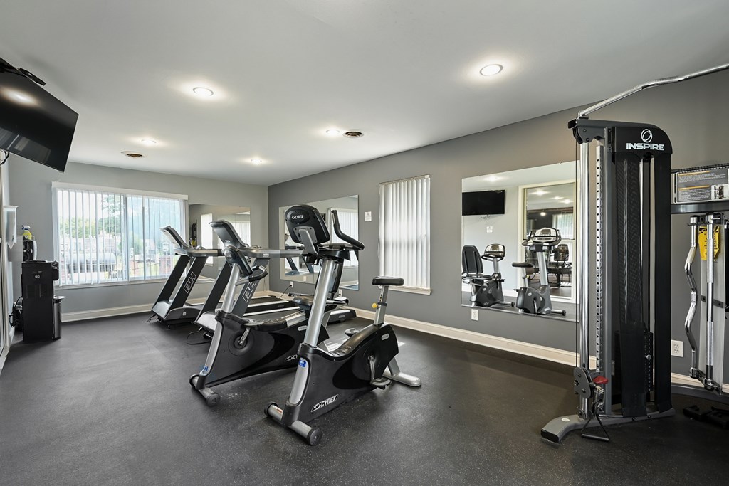 A gym with a row of exercise bikes and a weight rack.