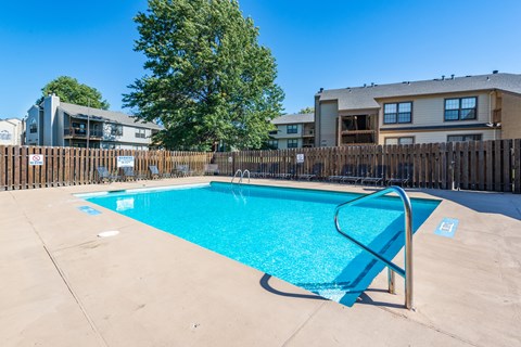our apartments have a swimming pool with a fence and apartment buildings