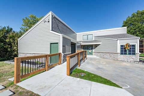 the deck and driveway of a house with a green door