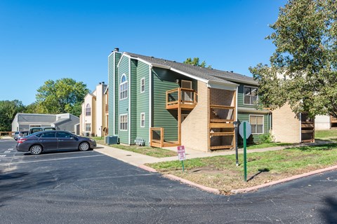 a green apartment building with a car parked in a parking lot