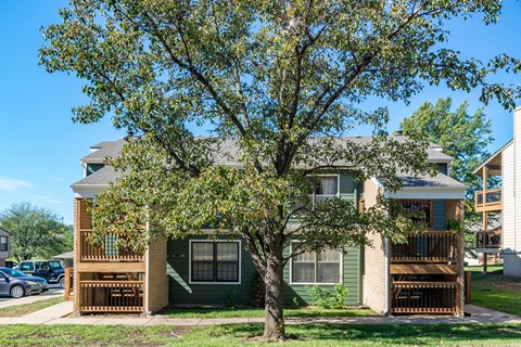 a green house with a tree in front of it