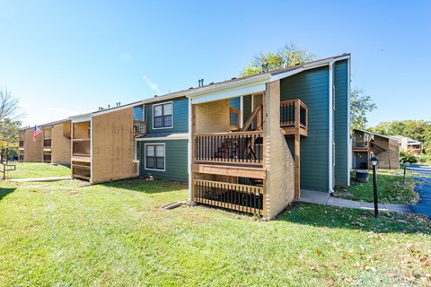 the exterior of an apartment building with stairs and a porch