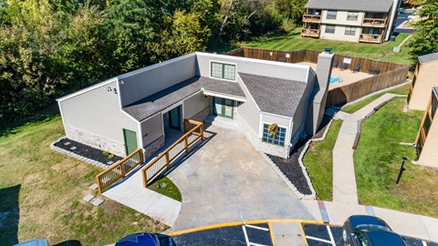 an aerial view of a white house with a gray roof and a yard with stairs