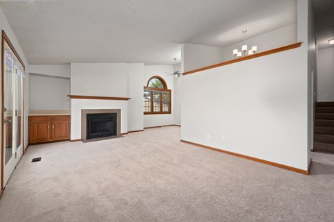 an empty living room with a fireplace and white walls