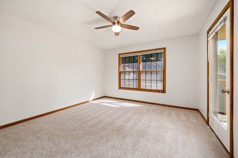 an empty living room with a ceiling fan and a window