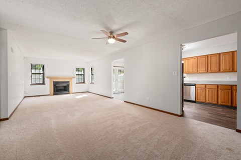 an empty living room with a ceiling fan and a fireplace