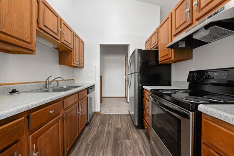 an empty kitchen with wood cabinets and black appliances