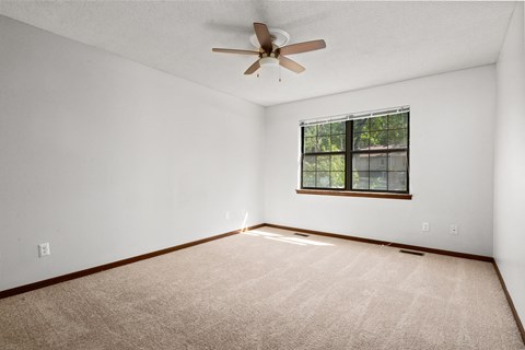an empty living room with a ceiling fan and a window
