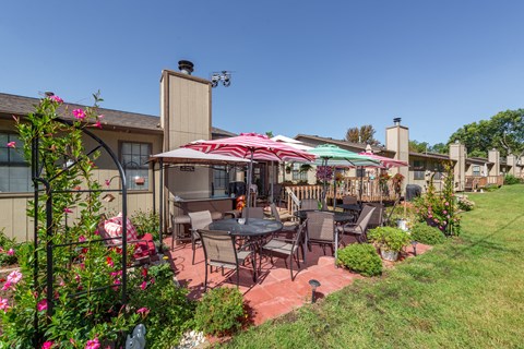 a patio with tables and umbrellas in a garden