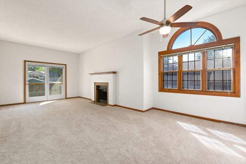an empty living room with a fireplace and a ceiling fan