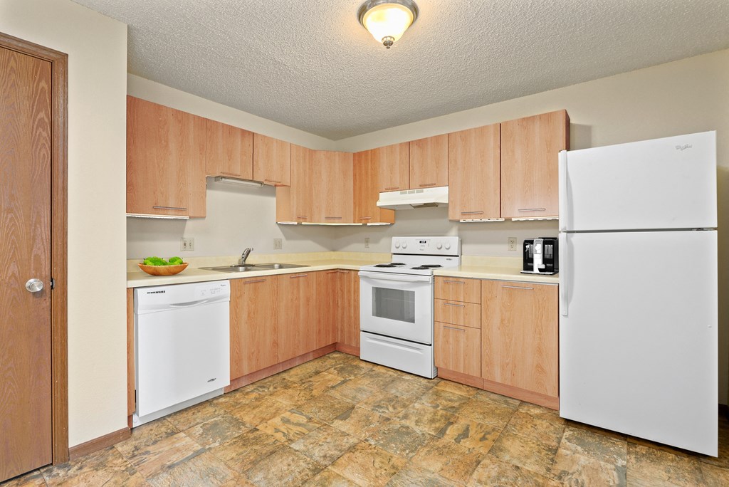 an empty kitchen with white appliances and wooden cabinets