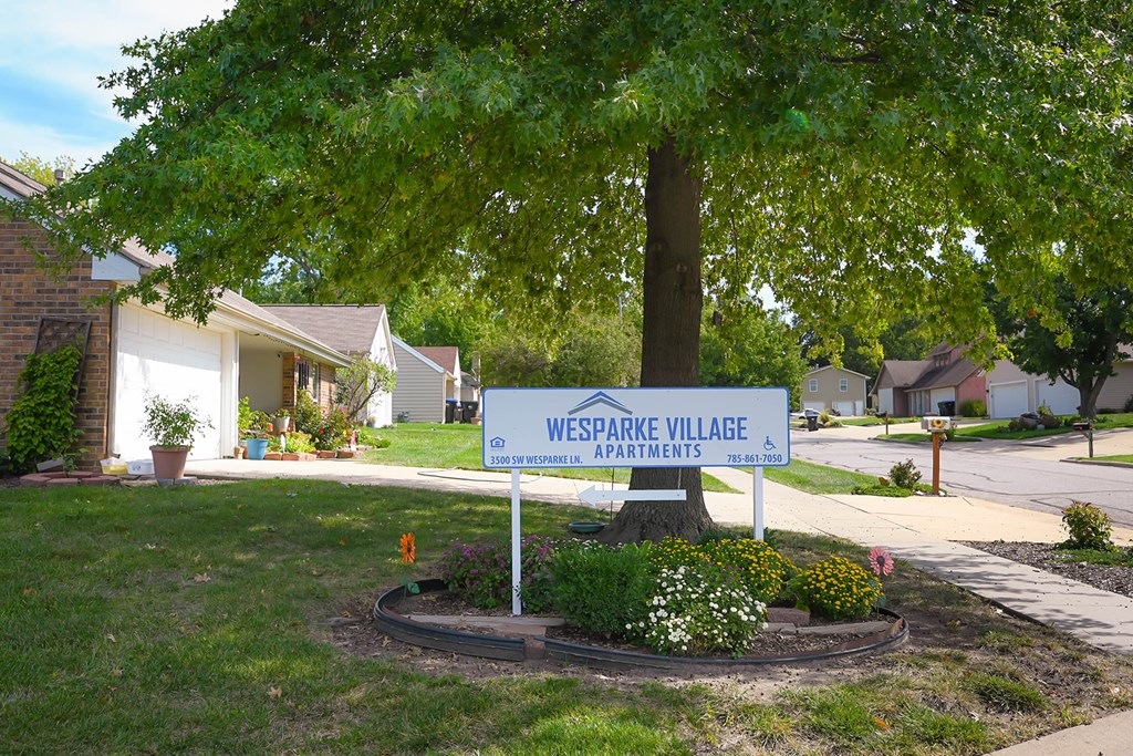 A sign for Wesparke Village Apartments stands in a landscaped area.