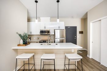 A kitchen with white countertops and a white bar stool.