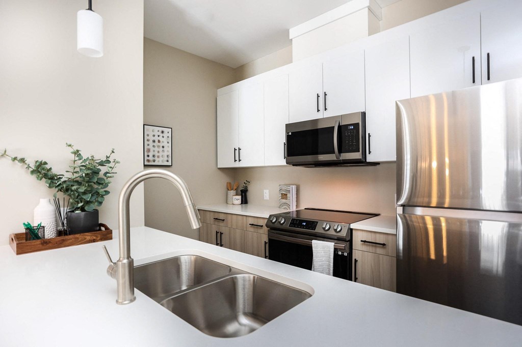 A modern kitchen with a stainless steel refrigerator and a sink with a faucet.