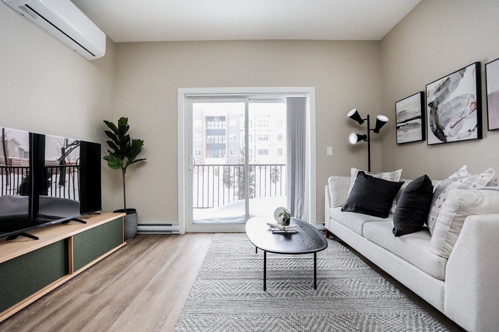 A living room with a white couch, a coffee table, and a television.