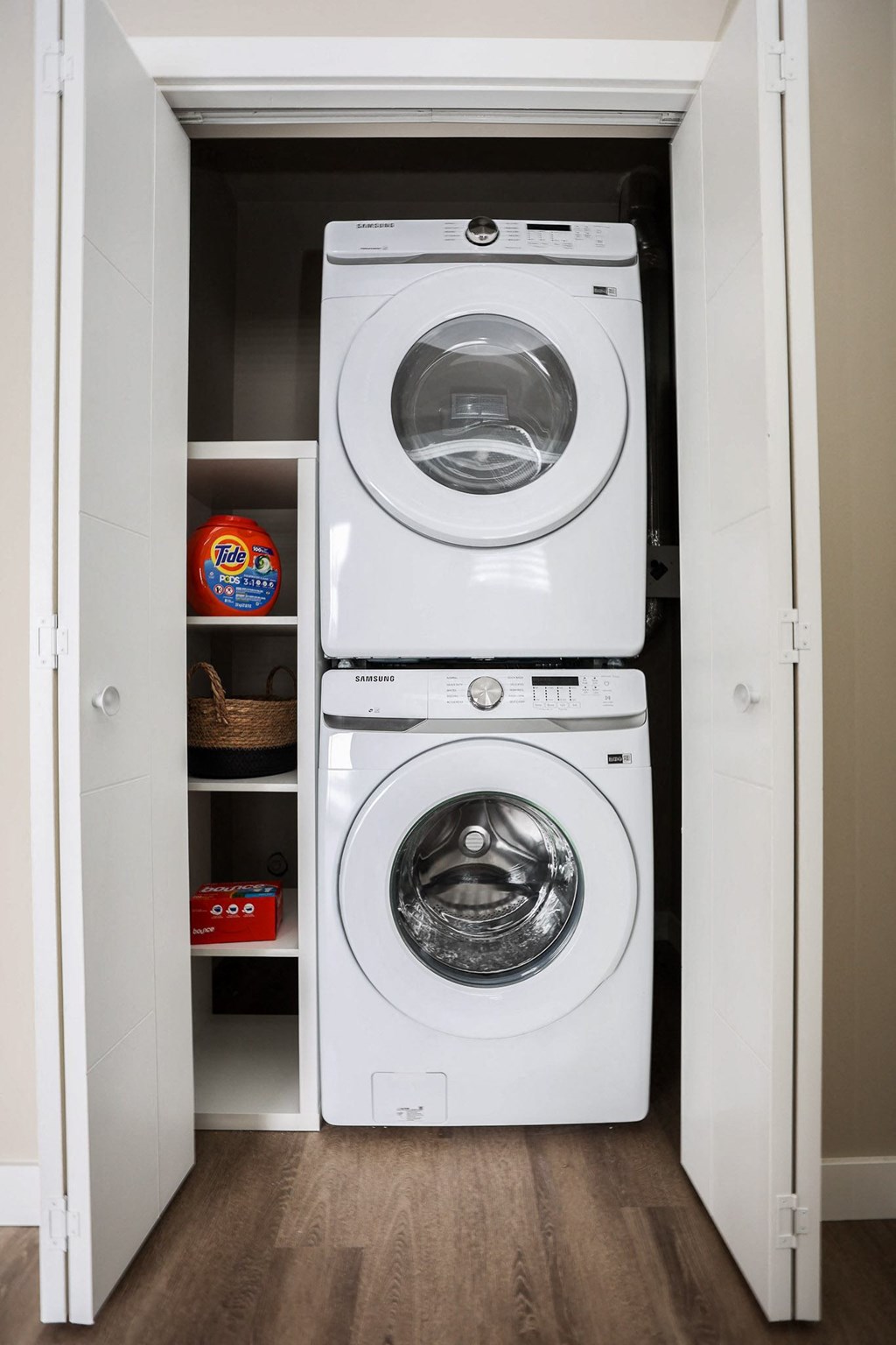A white dryer is on top of a white washing machine in a small laundry closet.