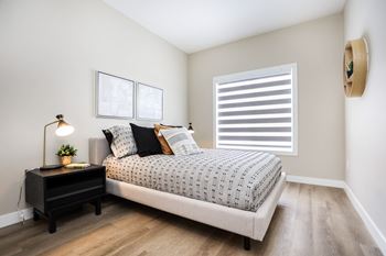 A bedroom with a bed, nightstand, and a lamp.