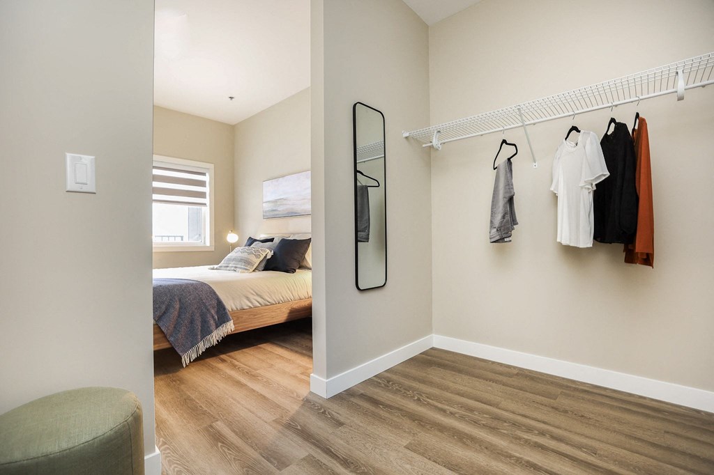 A bedroom with a bed, a chair, and clothes hanging on a rack.