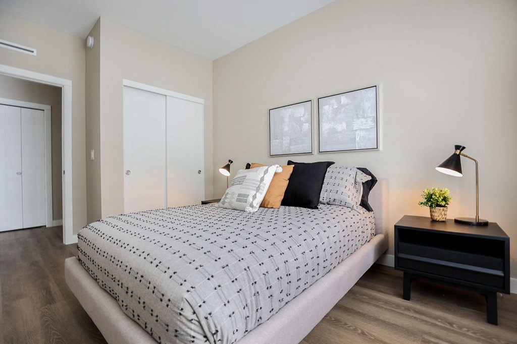 A bedroom with a large bed and a small table with a plant on it.