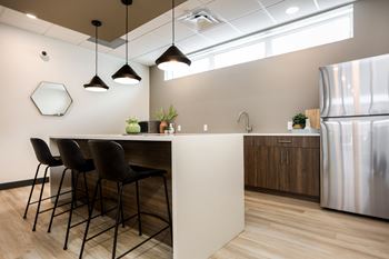 A modern kitchen with a white island and black chairs.