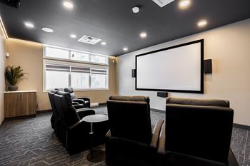 A room with a large screen and comfortable seating.