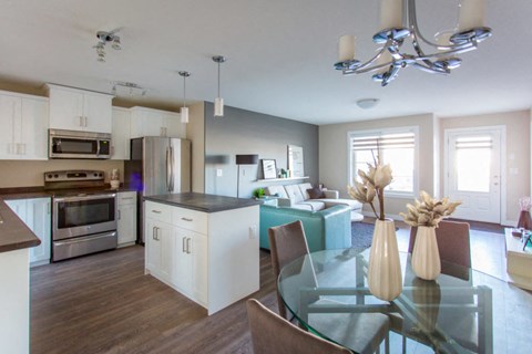 A modern kitchen with a glass table and chairs.