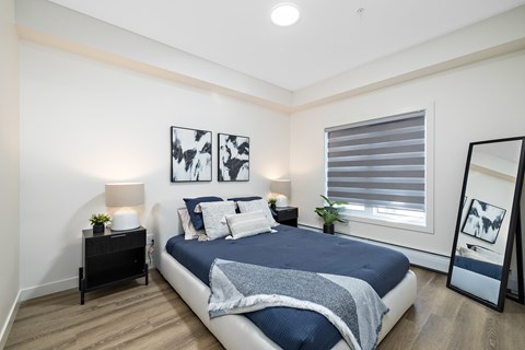Modern bedroom with navy blue bedding at Mac and Mullen Apartments, Alberta