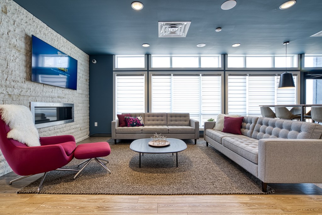 A living room with a red chair and a grey couch.