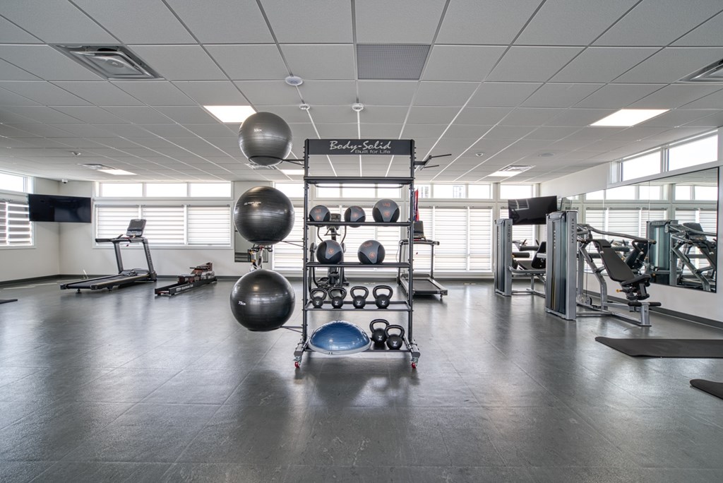 A gym with a variety of equipment including weights and exercise balls.