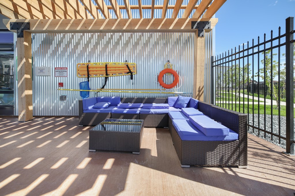 A wooden deck with a blue couch and a surfboard on the wall.