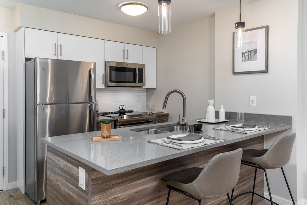 kitchen with stainless steel appliances and island with white quartz counter tops and white cabinets