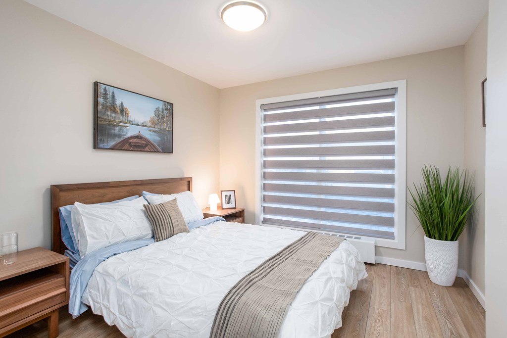 a bedroom with a bed and a window with blinds