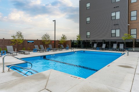 A large blue swimming pool in front of a tall building.