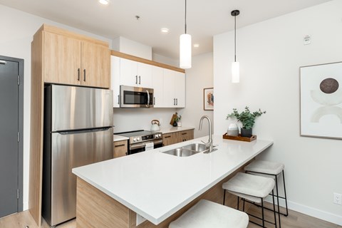 A modern kitchen with a stainless steel refrigerator and a white countertop.