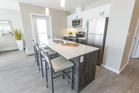 a kitchen with a large island and a stainless steel refrigerator