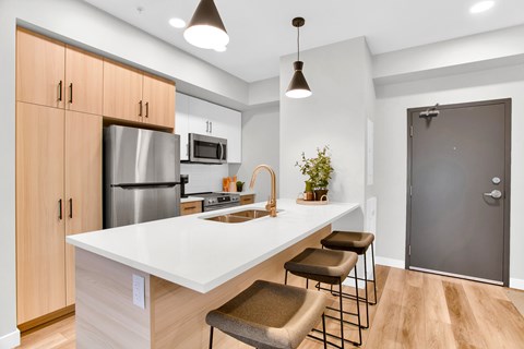 A kitchen with a white countertop and wooden cabinets.