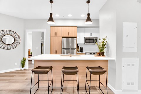 A modern kitchen with a white countertop and brown bar stools.