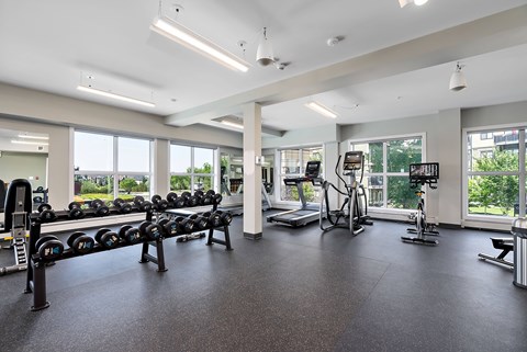 A gym with a variety of equipment including treadmills, weights, and exercise bikes.