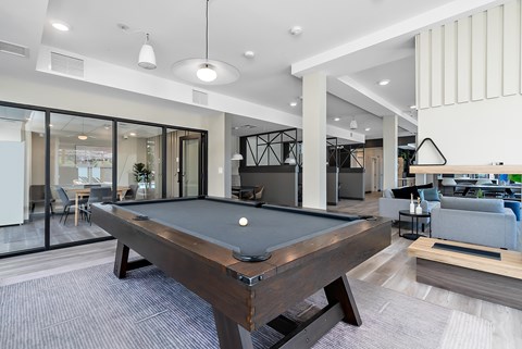 A pool table is in the middle of a room with a glass wall.