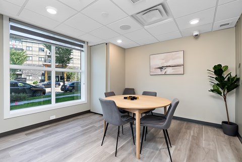 A conference room with a table, chairs, and a plant.