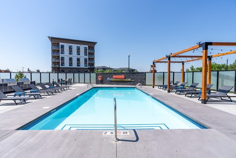A large swimming pool with a diving board and lounge chairs.