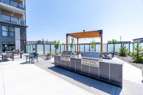 A modern outdoor kitchen area with a grill and seating area.